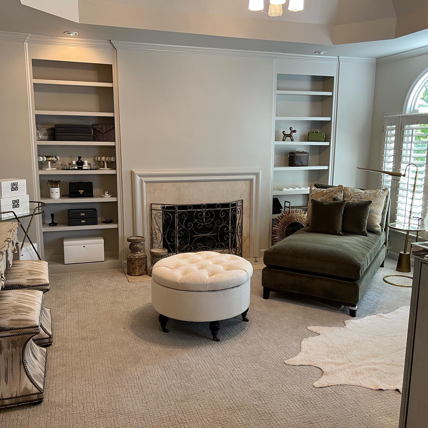 Styled living room with built-in bookshelves displaying jewelry and accessories, a fireplace, and a velvet chaise by Imagine Organizing — Interior Design in Riverdale