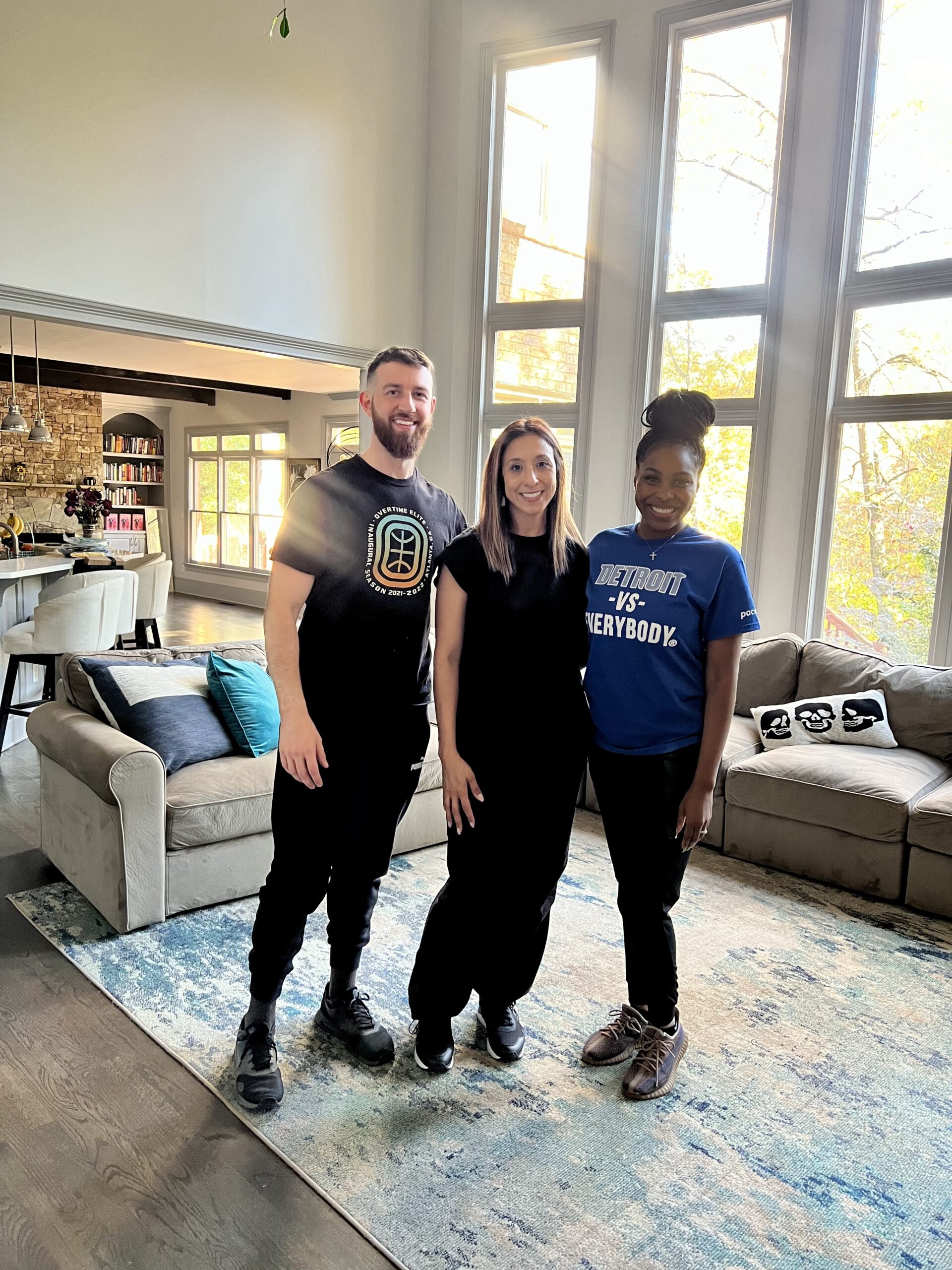 Three Imagine Organizing team members smiling together in a bright, high-ceilinged living room — Concierge Services in Brookhaven