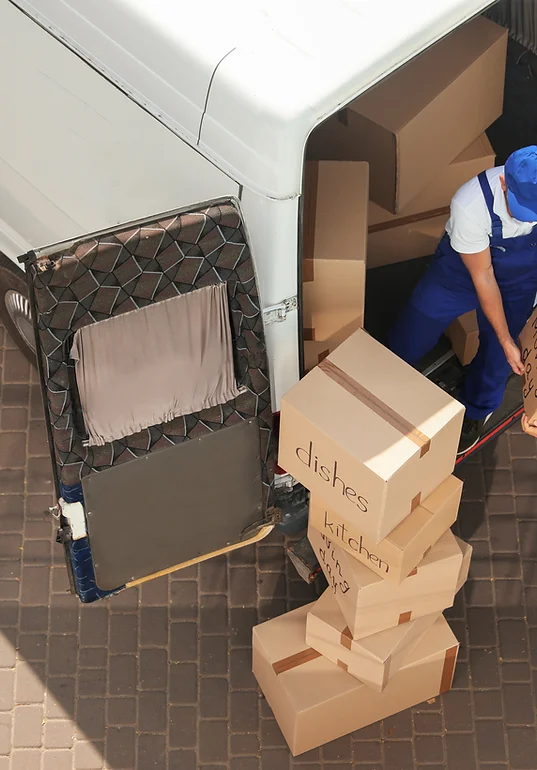 Mover in blue coveralls loading labeled kitchen and dishes boxes into a moving truck — Moving Services in Decatur