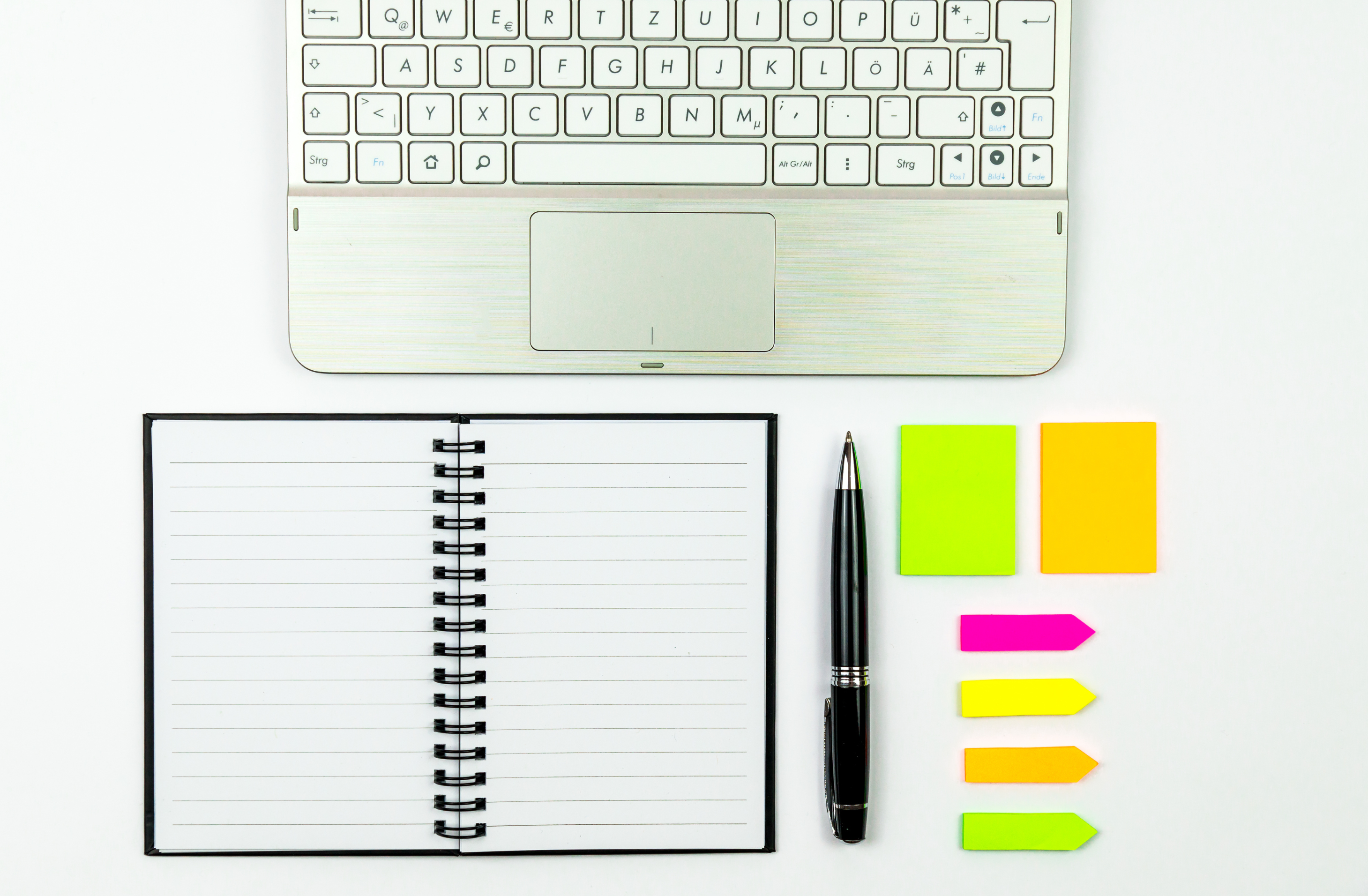 Flat lay of a notebook, pen, and colorful sticky note tabs on a white desk — Concierge Services in Brookhaven