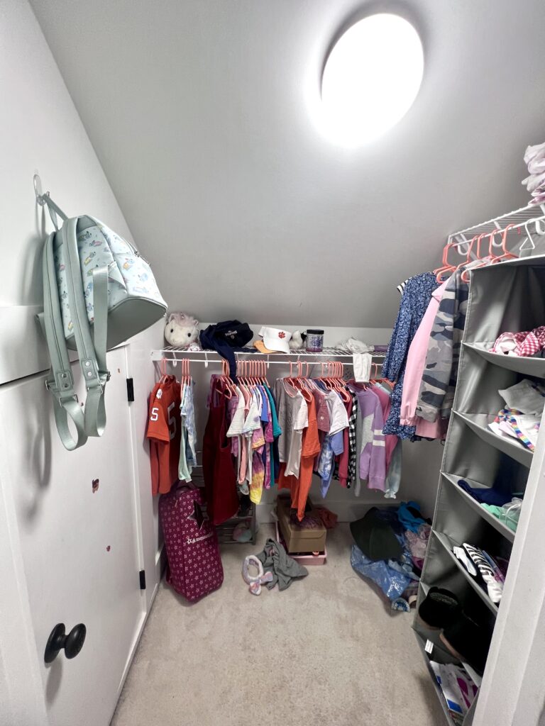 Kids' closet under a sloped ceiling with hanging clothes and labeled storage bins by Imagine Organizing