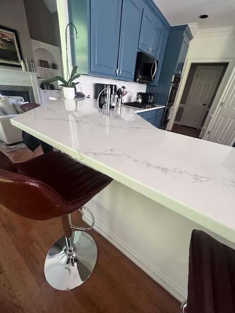 Kitchen island seating with leather stools and a quartz countertop in a blue cabinet kitchen — Interior Design in Riverdale