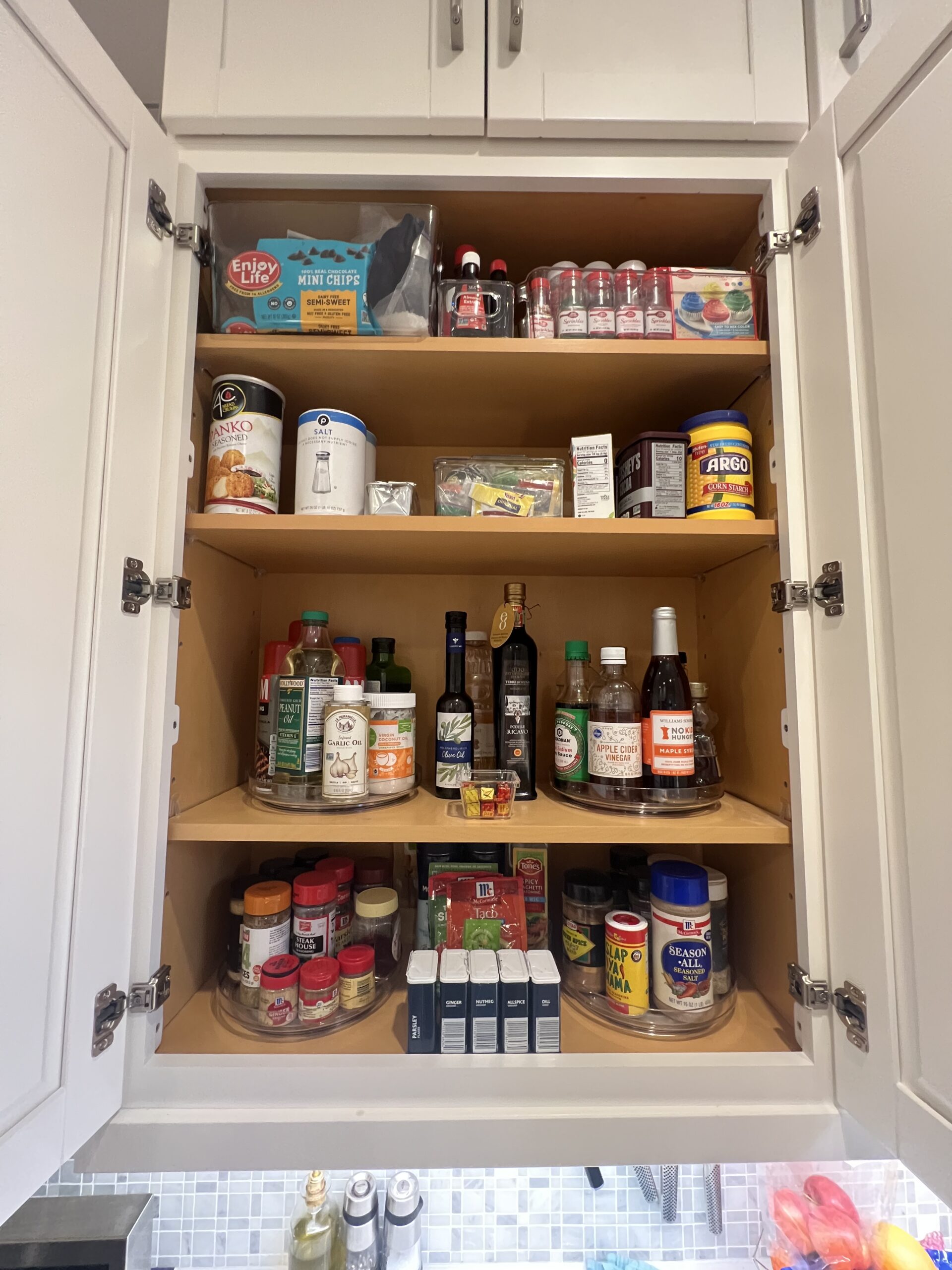 Organized kitchen cabinet with baking ingredients, oils, and pantry staples arranged for easy access by Imagine Organizing — Home Organizing in Tucker