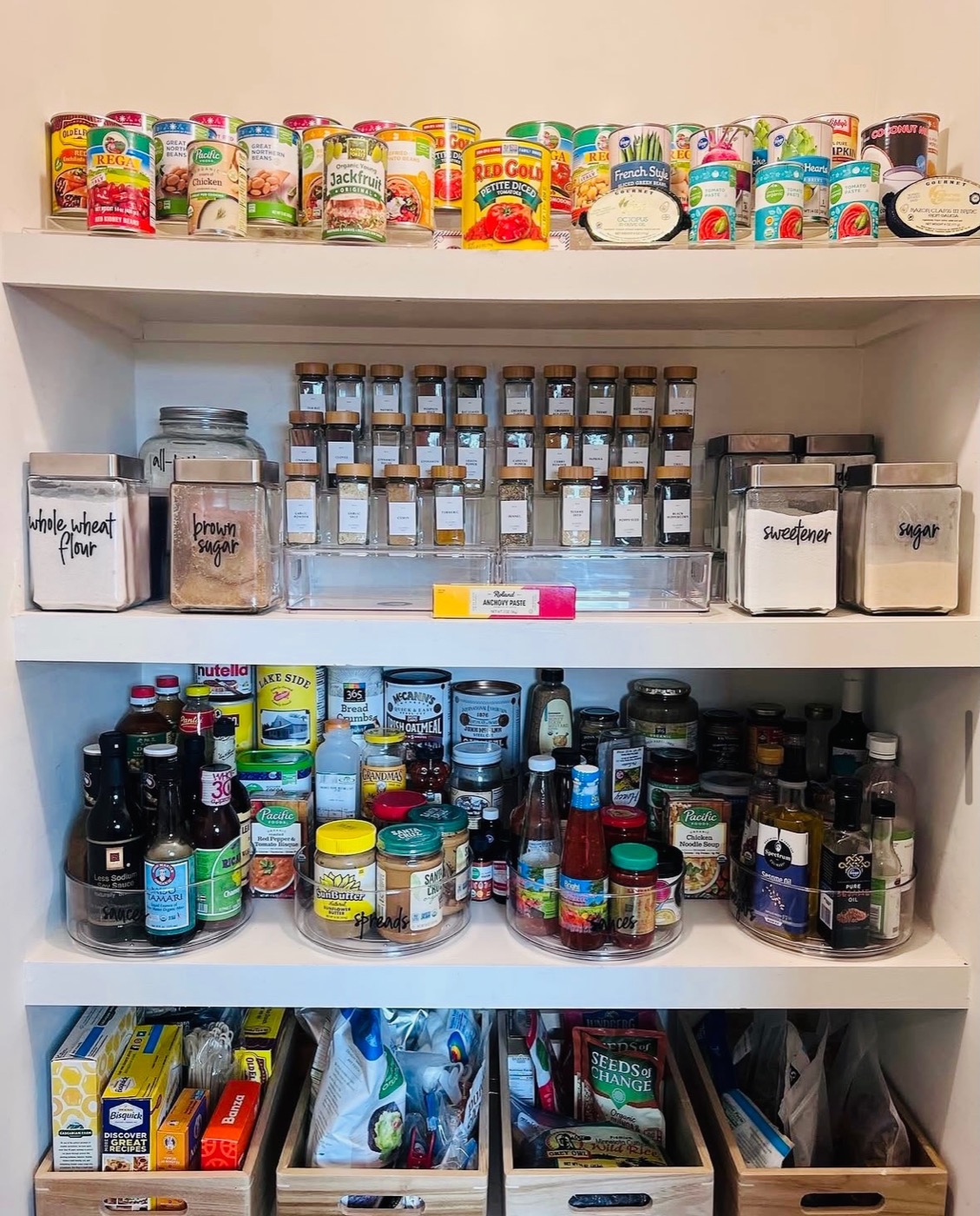 Organized pantry shelves with labeled flour and sugar canisters, spice jars and lazy susans — Interior Design in Riverdale